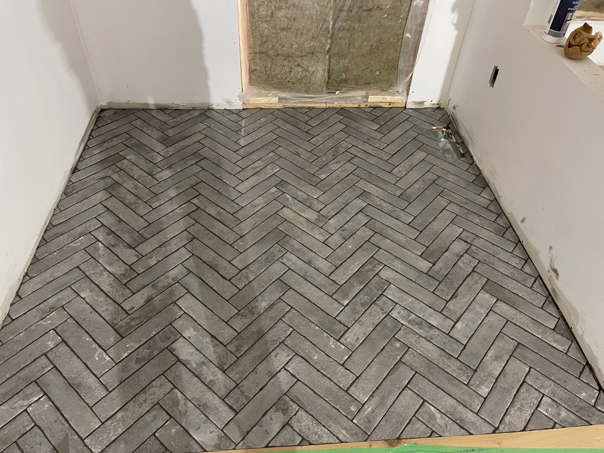 Gray herringbone floor tile installation